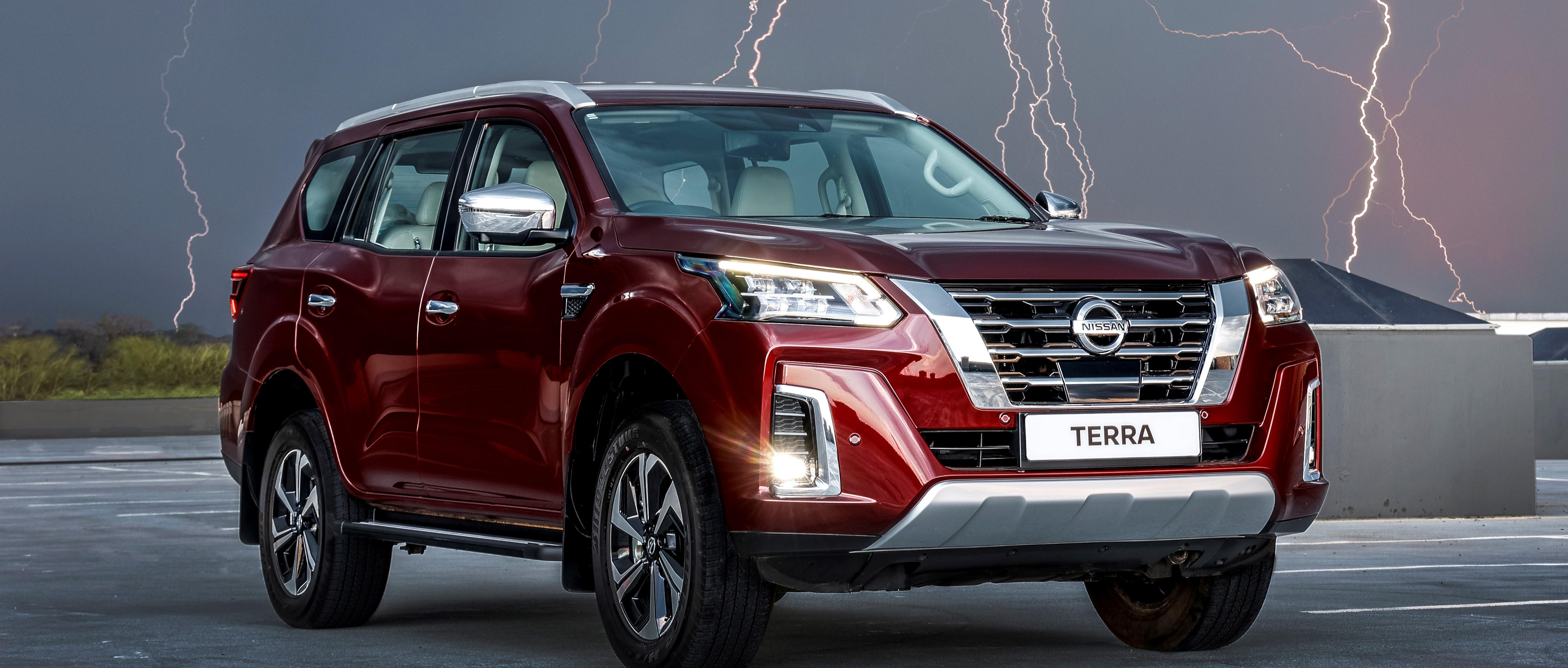 Red Nissan Terra in open field with lighting in background